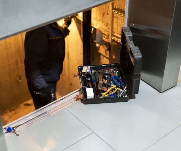 Specialist fixing or adjusting lift mechanism in elevator schaft. Regular repair, service and maintenance of elevator
